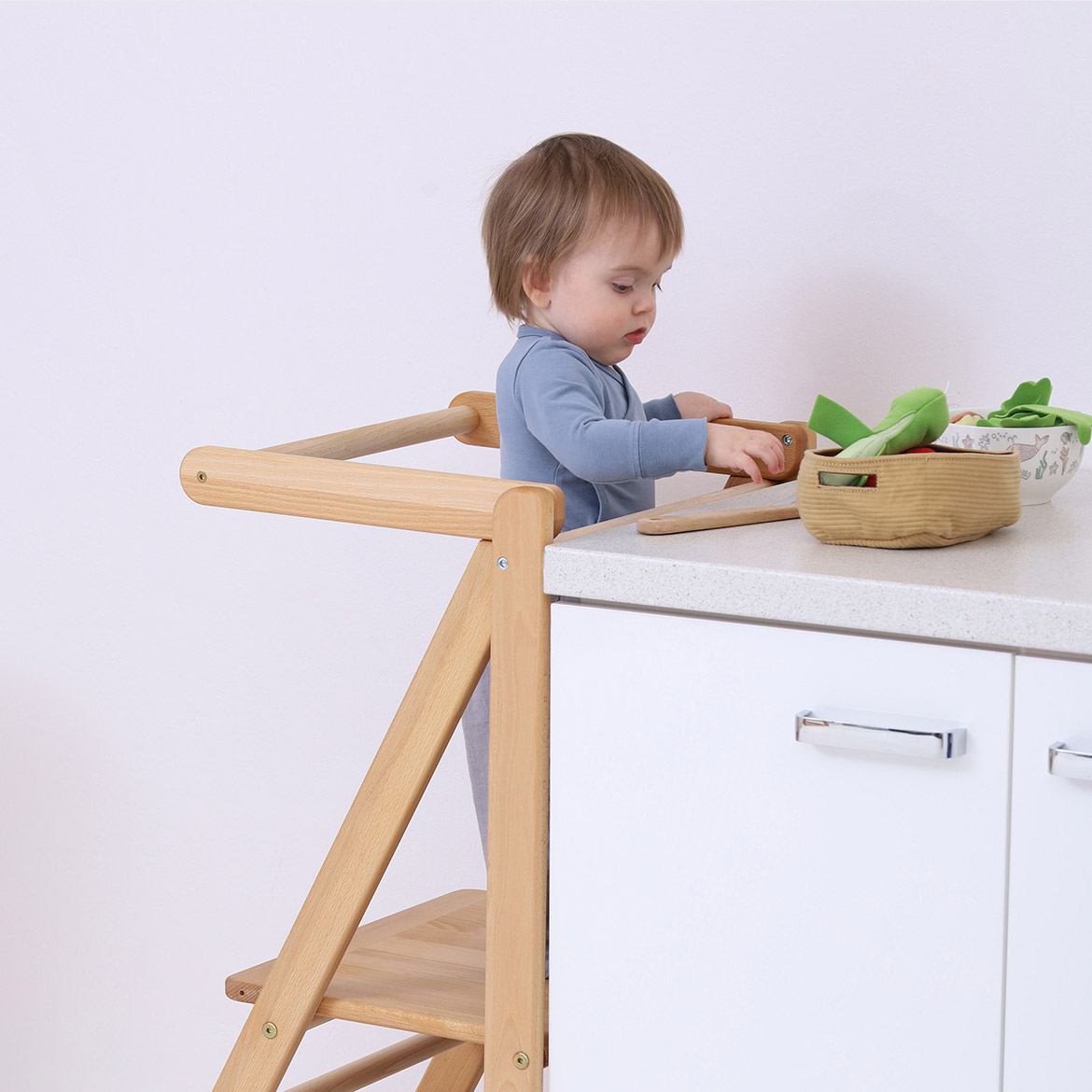 Toddler standing independently on MONTEtower foldable Montessori learning tower, reaching kitchen counter by Brubi