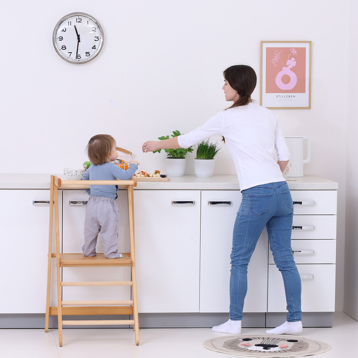 Child and mother working at kitchen counter, child using MONTEtower foldable Montessori learning tower by Brubi